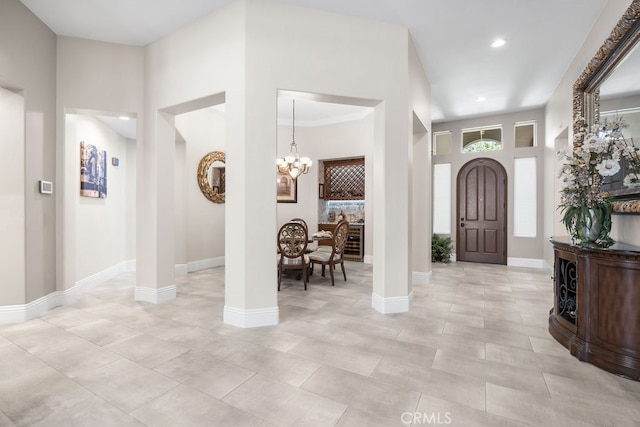 foyer entrance with decorative columns and an inviting chandelier