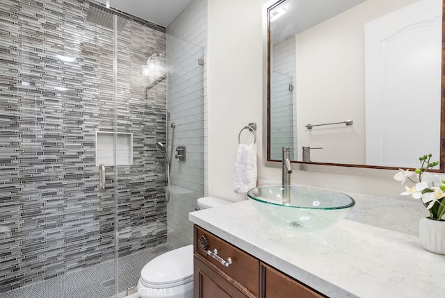 bathroom featuring vanity, toilet, and a shower with door