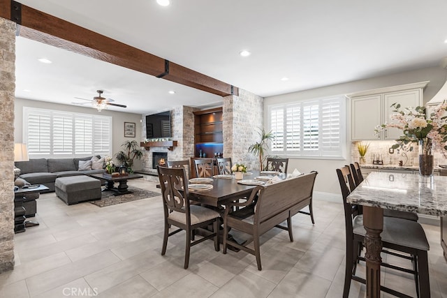 tiled dining space featuring a fireplace and ceiling fan