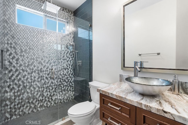 bathroom with vanity, toilet, and a shower with door