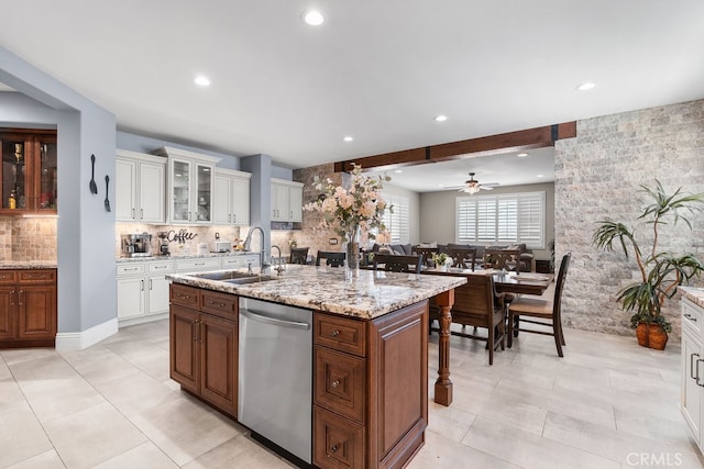 kitchen with dishwasher, a center island with sink, sink, ceiling fan, and tasteful backsplash