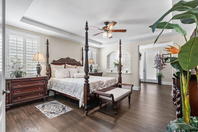 bedroom with ceiling fan, a raised ceiling, and dark hardwood / wood-style floors