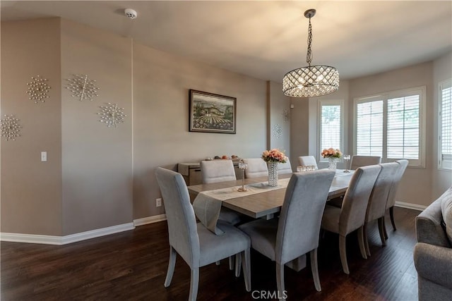 dining space with dark wood-type flooring and a notable chandelier