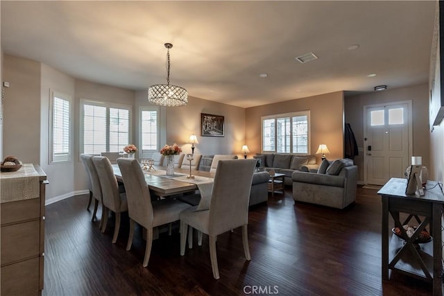 dining room with dark hardwood / wood-style flooring and an inviting chandelier