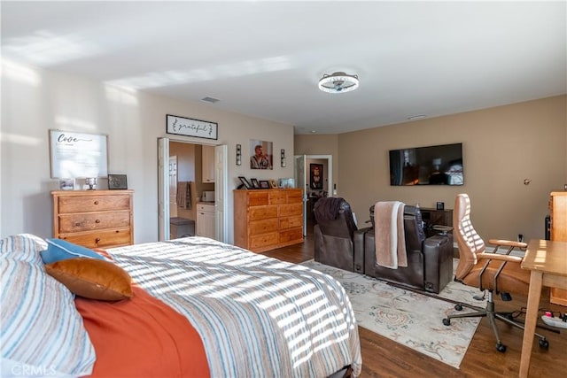 bedroom featuring connected bathroom and dark hardwood / wood-style floors