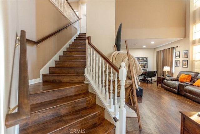 stairs featuring wood-type flooring and a high ceiling