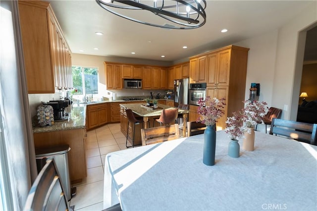 kitchen with a center island, sink, stainless steel appliances, a kitchen breakfast bar, and light tile patterned floors