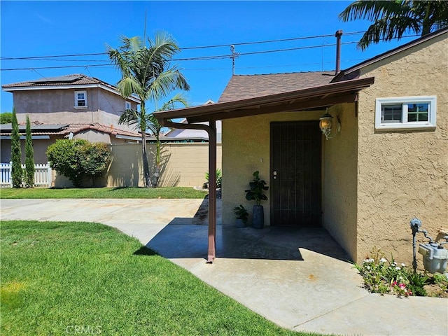 view of exterior entry featuring a lawn and a patio