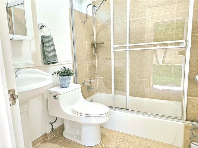 bathroom featuring toilet, tile patterned floors, and bath / shower combo with glass door