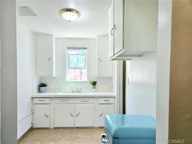 kitchen featuring backsplash, white cabinetry, tile counters, and sink