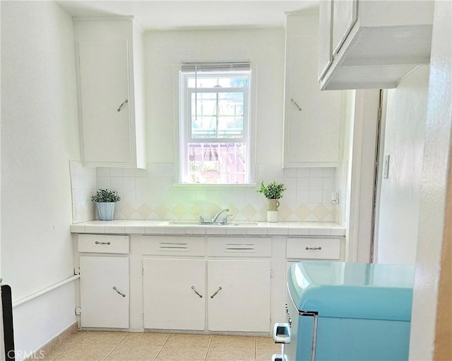 kitchen with tasteful backsplash, tile countertops, white cabinetry, and sink