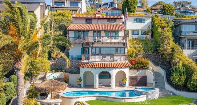 rear view of property with stucco siding, a residential view, a pool with connected hot tub, and a patio area