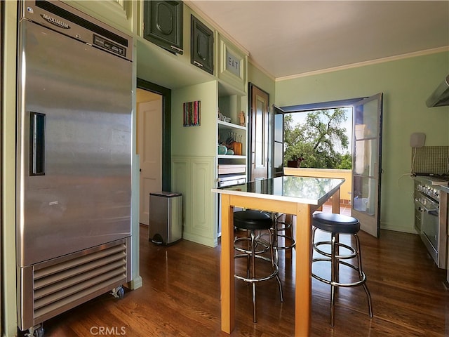 kitchen with a kitchen island, dark hardwood / wood-style floors, stainless steel built in refrigerator, a kitchen breakfast bar, and crown molding