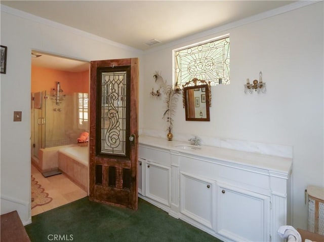 bathroom featuring a bathing tub, ornamental molding, and vanity