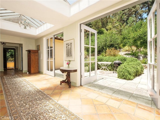 doorway with lofted ceiling with skylight, plenty of natural light, and french doors