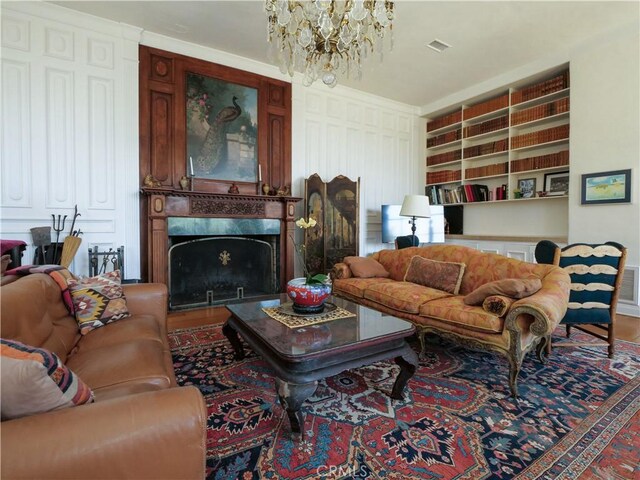 living room featuring wood-type flooring, an inviting chandelier, and a high end fireplace