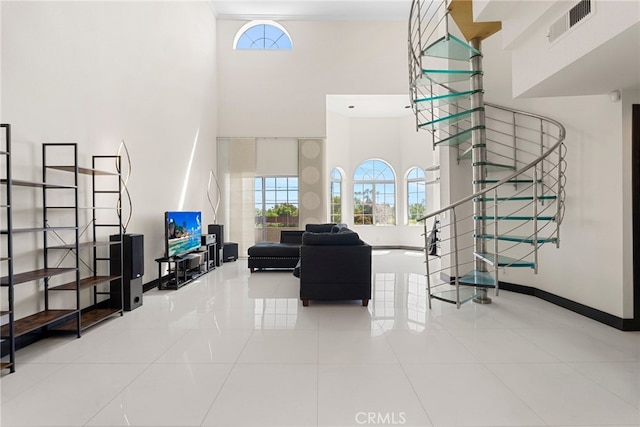 living room with tile patterned flooring, visible vents, a towering ceiling, and baseboards