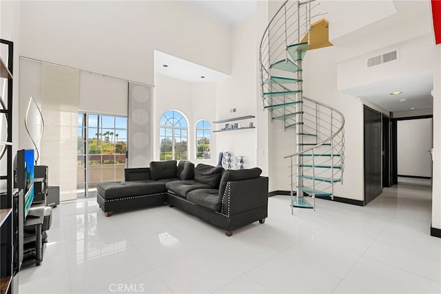 living room featuring stairs, a high ceiling, visible vents, and tile patterned floors