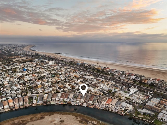 aerial view at dusk featuring a water view and a view of the beach