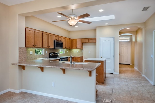 kitchen featuring a kitchen bar, sink, kitchen peninsula, stainless steel appliances, and decorative backsplash