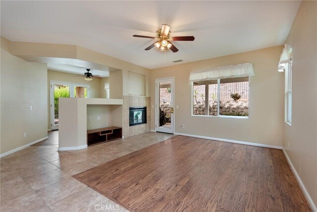 unfurnished living room featuring a tiled fireplace and ceiling fan