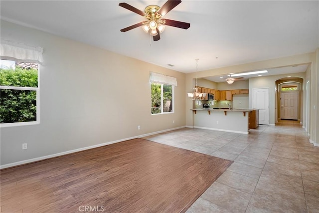 unfurnished living room featuring light hardwood / wood-style floors and ceiling fan with notable chandelier