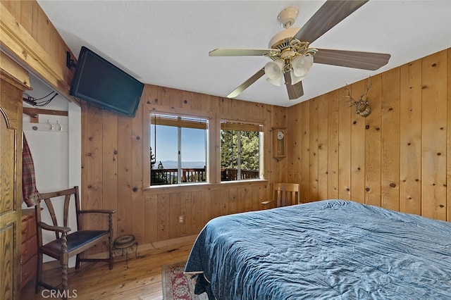 bedroom with wooden walls, ceiling fan, and hardwood / wood-style flooring