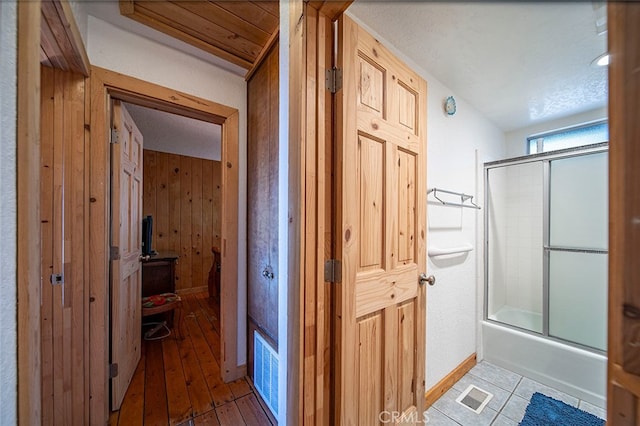 hall with light hardwood / wood-style flooring and wood walls