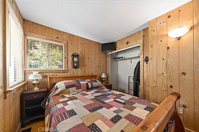 bedroom with wood walls, a closet, and a textured ceiling