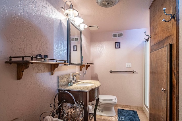 bathroom with vanity, a textured ceiling, tile patterned floors, walk in shower, and toilet