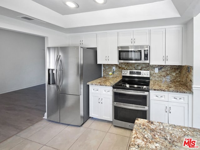 kitchen featuring light tile patterned flooring, white cabinetry, backsplash, appliances with stainless steel finishes, and light stone countertops