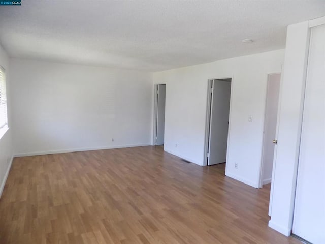 empty room with wood-type flooring and a textured ceiling