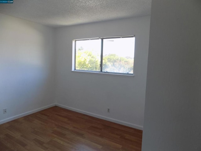 empty room featuring dark hardwood / wood-style flooring, a textured ceiling, and a wealth of natural light