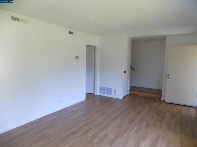 empty room featuring a textured ceiling and light hardwood / wood-style floors