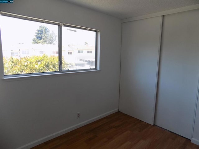 empty room with dark hardwood / wood-style flooring and a textured ceiling