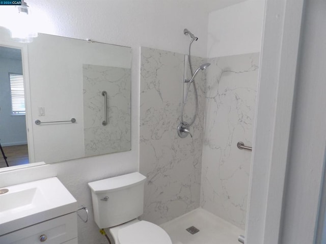 bathroom featuring toilet, vanity, and tiled shower