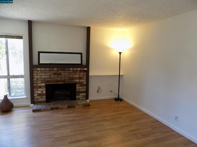 unfurnished living room with hardwood / wood-style floors, a textured ceiling, and a wealth of natural light