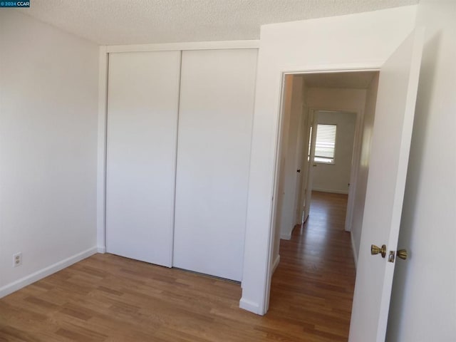 unfurnished bedroom with a closet, wood-type flooring, and a textured ceiling