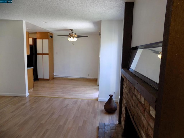 spare room with a textured ceiling, light wood-type flooring, and ceiling fan