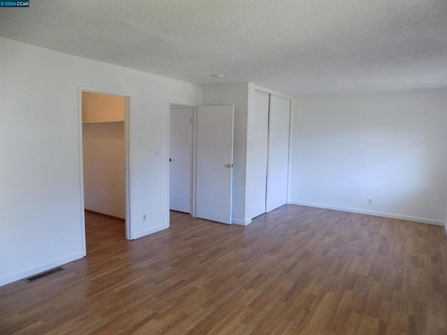 unfurnished bedroom featuring a textured ceiling and dark hardwood / wood-style floors