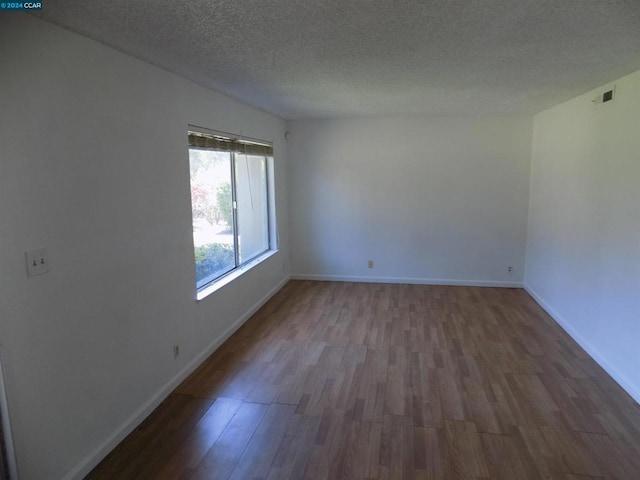 empty room with hardwood / wood-style floors and a textured ceiling