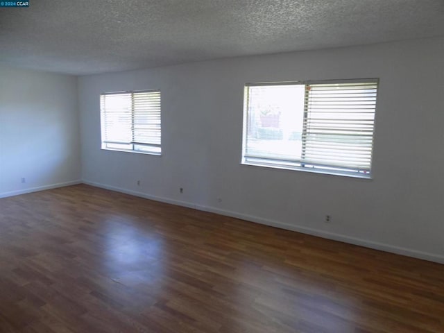 unfurnished room with a textured ceiling and dark wood-type flooring