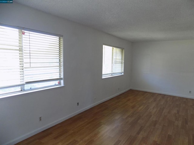 unfurnished room with dark hardwood / wood-style floors and a textured ceiling