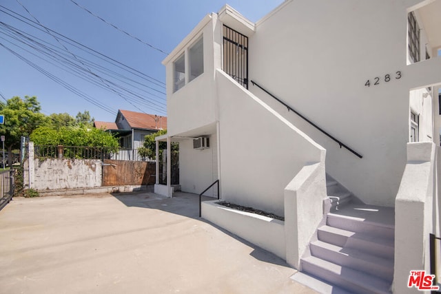 exterior space with a wall mounted air conditioner