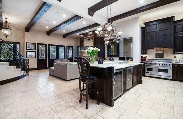 kitchen with hanging light fixtures, an island with sink, a kitchen breakfast bar, beamed ceiling, and double oven range