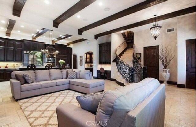 living room with beamed ceiling and an inviting chandelier