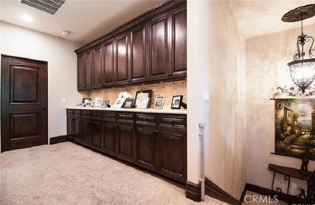 bar with decorative backsplash, dark brown cabinetry, decorative light fixtures, and light colored carpet