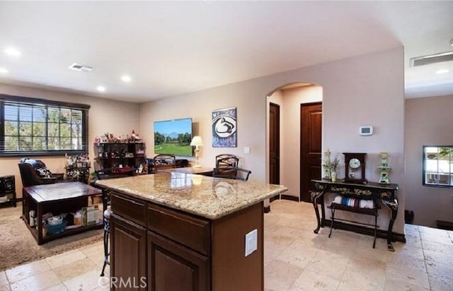 kitchen featuring light stone counters, dark brown cabinetry, and a kitchen island