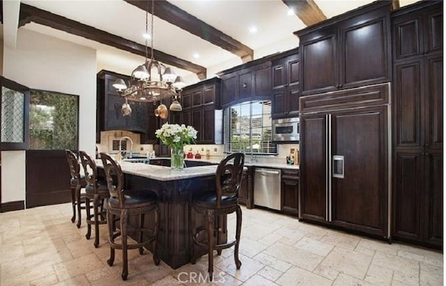 kitchen featuring a breakfast bar, decorative light fixtures, dark brown cabinets, appliances with stainless steel finishes, and beamed ceiling