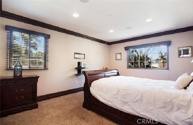 carpeted bedroom featuring crown molding and multiple windows